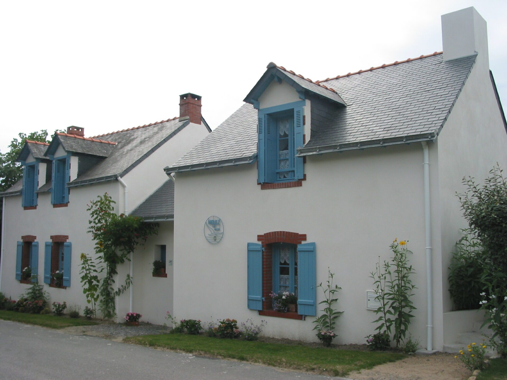 Maison avec toiture en ardoises et volets en bois bleu ciel