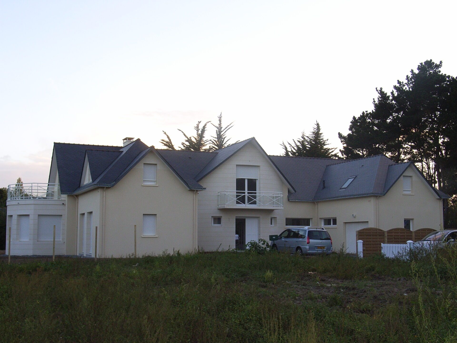 Maison avec bardage bois et grandes baies vitrées ainsi qu'une toiture en ardoise