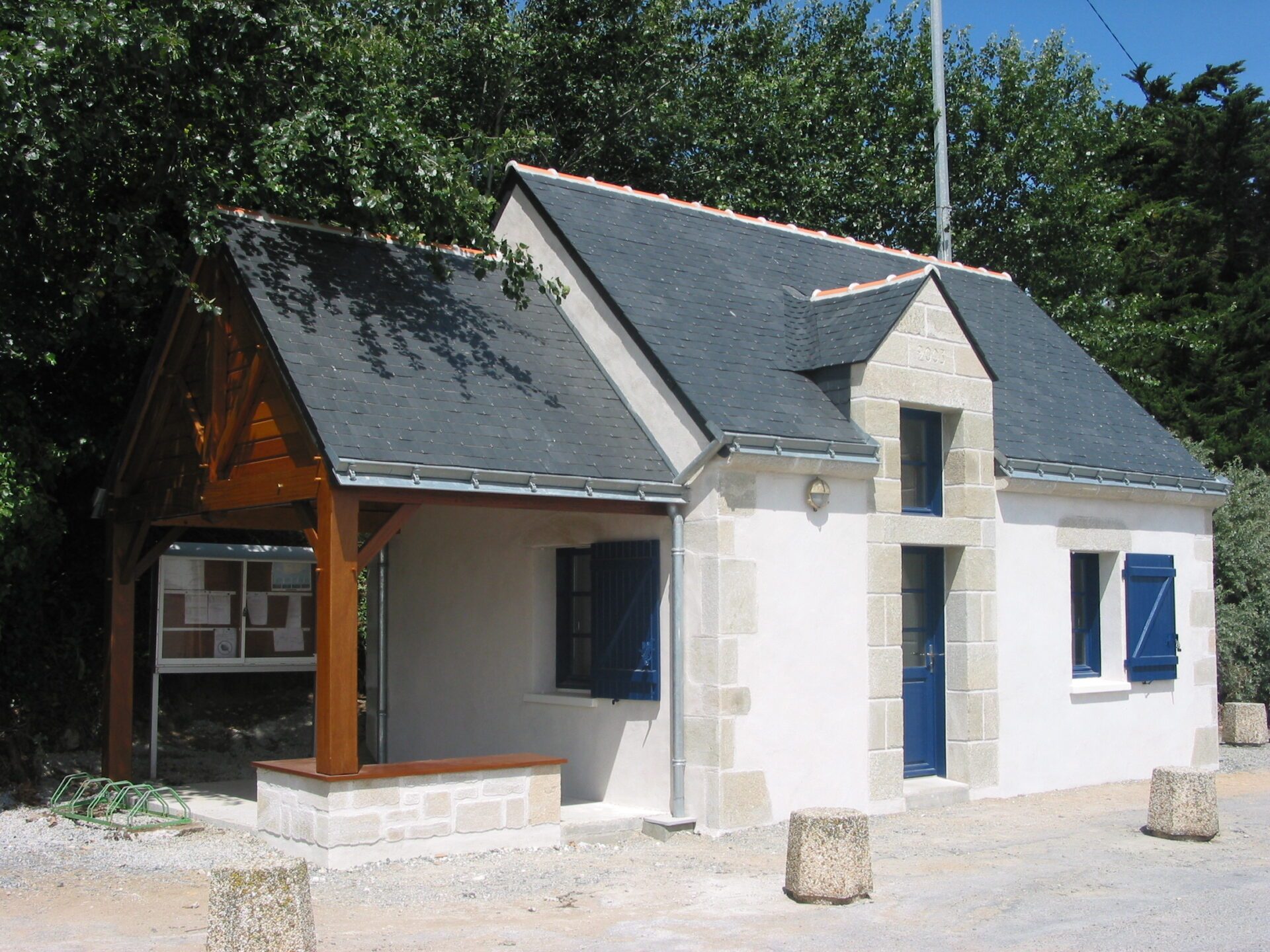 Maison avec parement en pierres, toit en ardoise et menuiseries en bois foncé