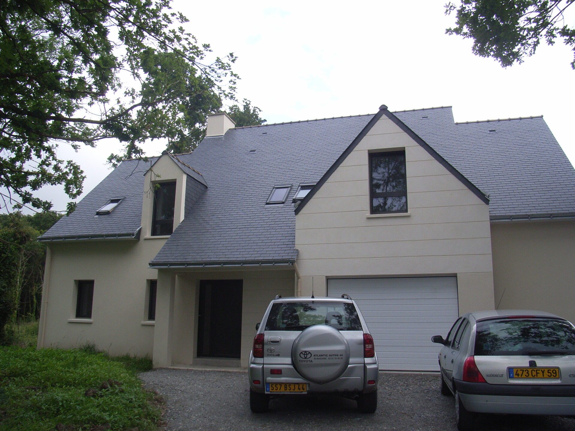 Maison avec bardage aluminium et grandes baies vitrées ainsi qu'une toiture en ardoise